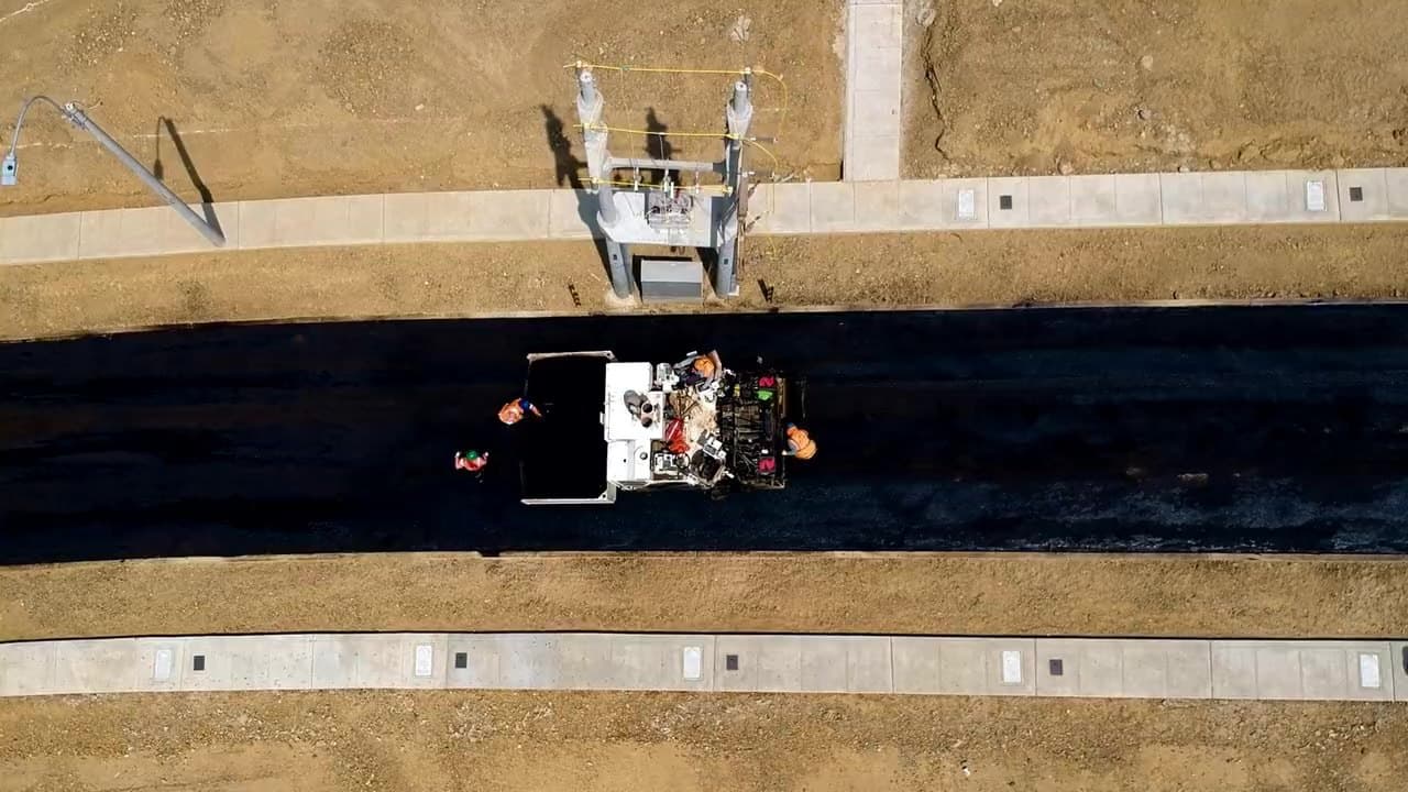 A paving crew laying fresh asphalt on a road